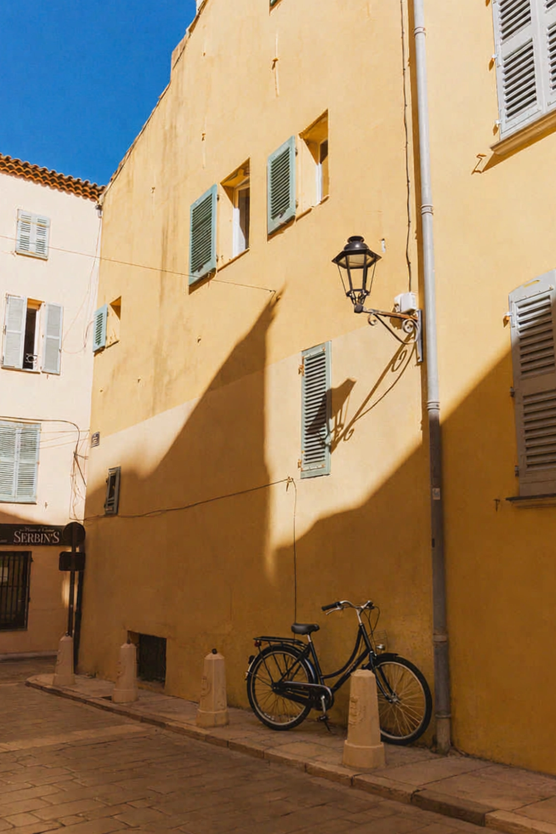 élo de ville stationné dans une ruelle ensoleillée aux façades ocres de Saint-Tropez, idéal pour une balade authentique en Provence.