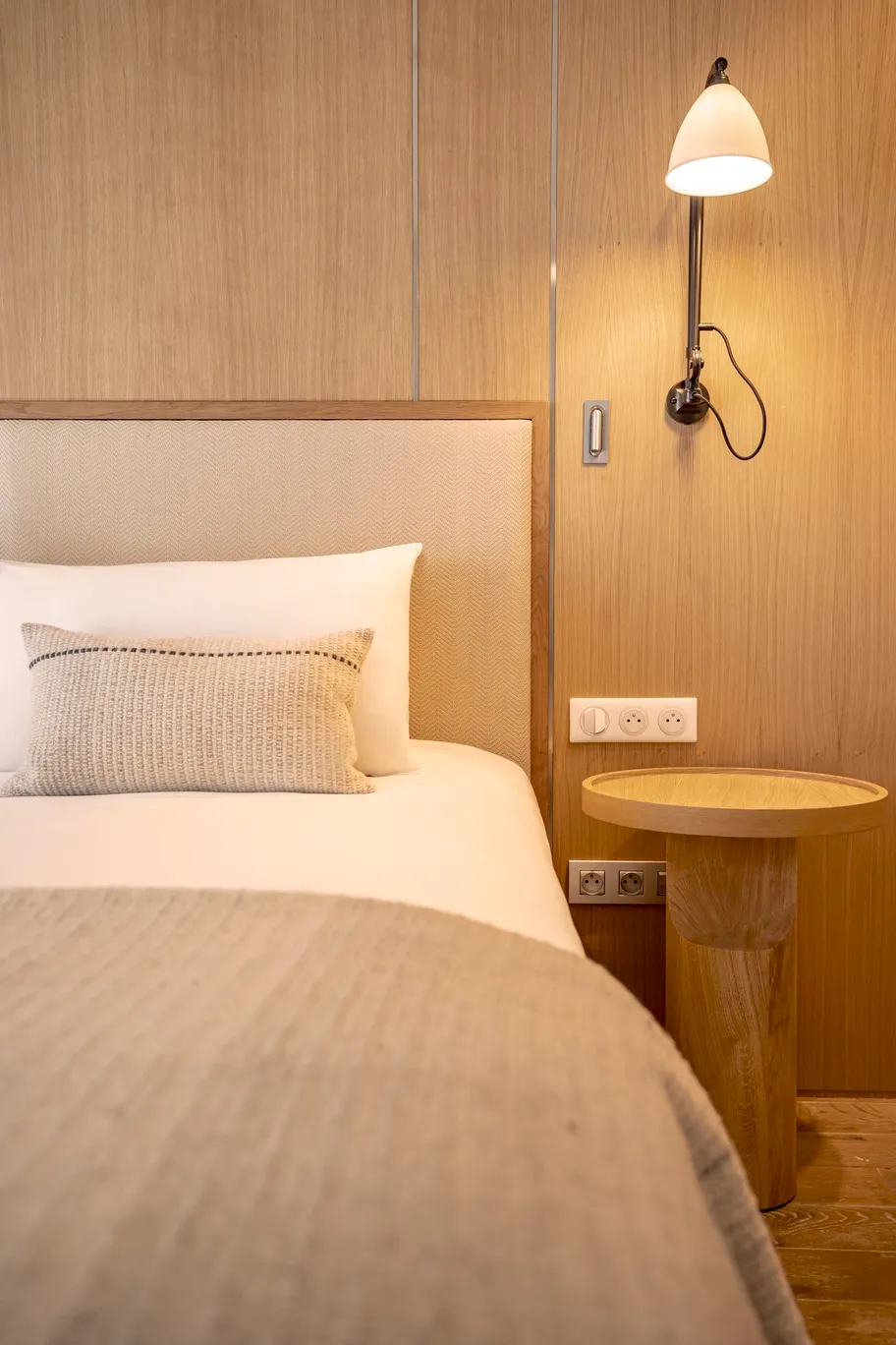 able de nuit artisanale en bois brut et applique murale élégante dans une chambre au style bord de mer chic.