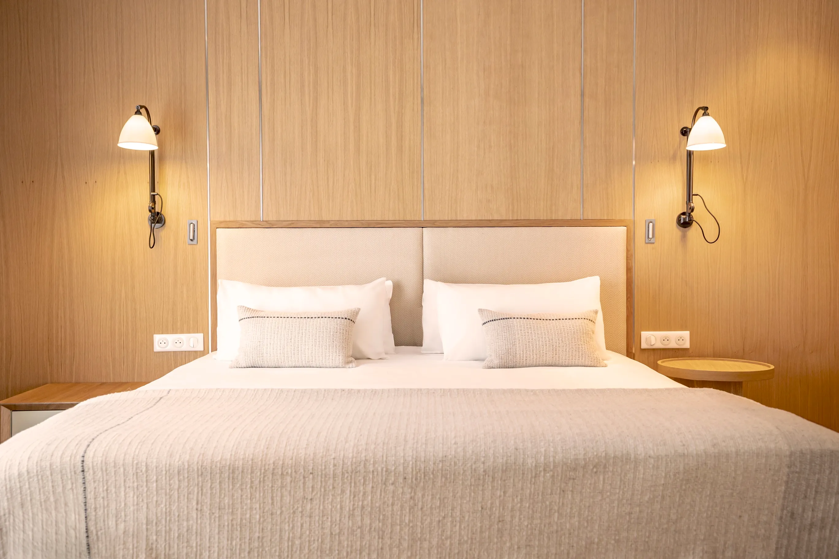 Prestige au design naturel avec habillage mural en bois noble, literie king-size et éclairage d'ambiance raffiné.