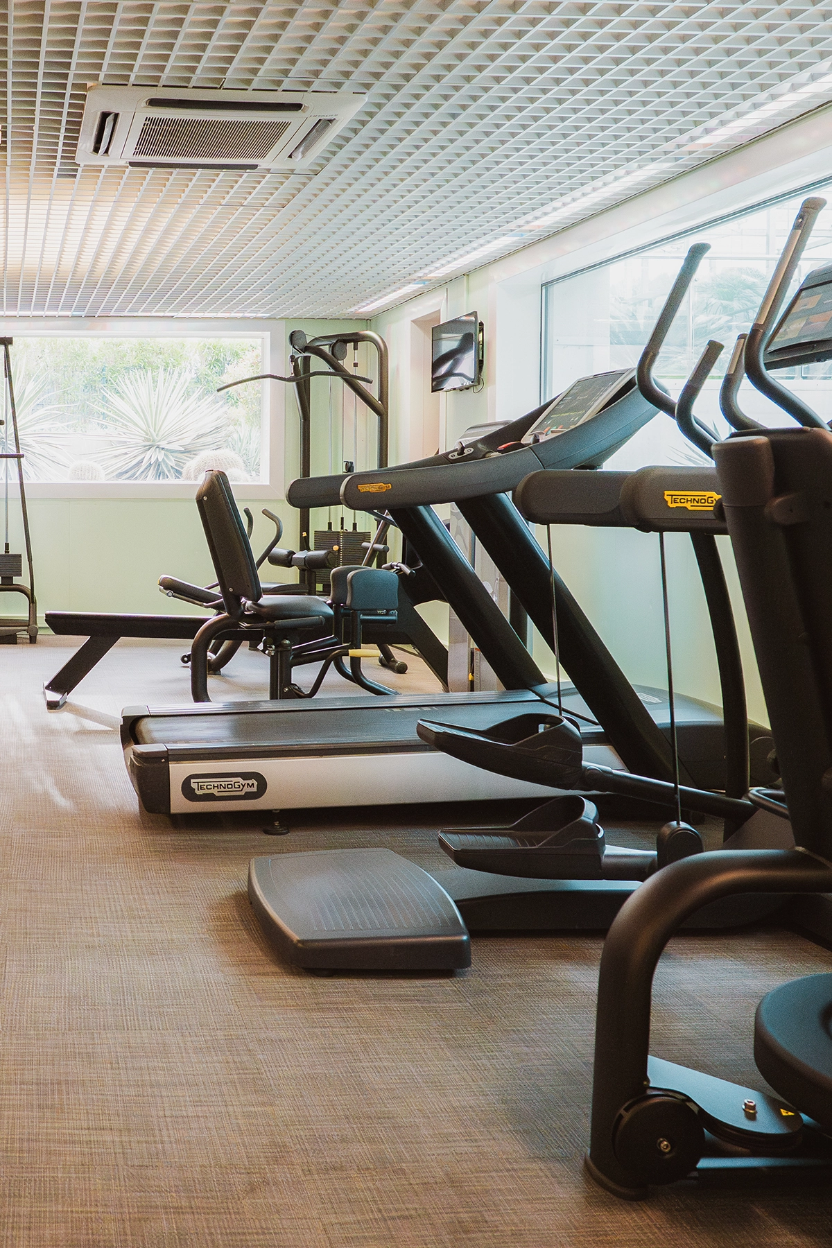 Espace cardio avec tapis de course modernes et machines de fitness à l'Hôtel Kube, avec vue lumineuse.