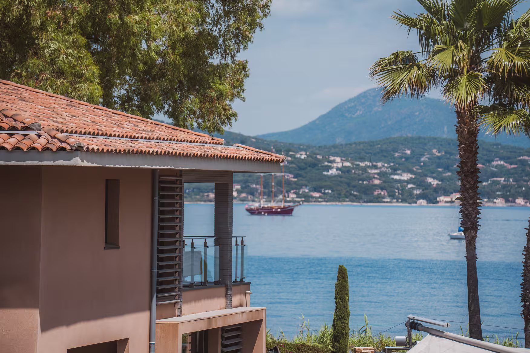 Le golfe de Saint-Tropez vu du Kube Saint-Tropez, un voilier au mouillage devant les collines boisées